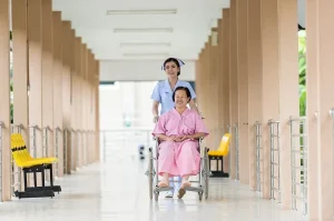 オーストラリアの病院で患者の車椅子を押す看護師