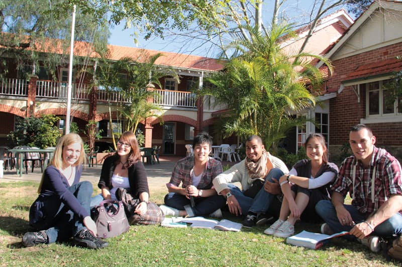 フェニックスアカデミーのキャンパスの芝生に座る学生たち