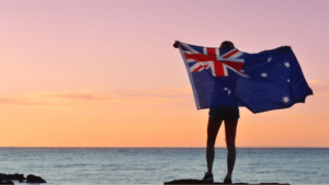 海に向かってオーストラリアの国旗を掲げる男性